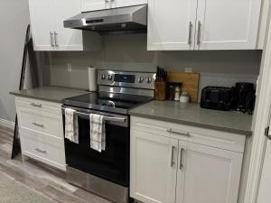 a kitchen with a black stove and white cabinets at Modern Private Suite close to the Airport & Border in Windsor +5 photos