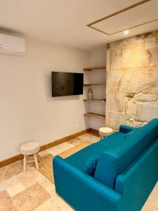 a living room with a blue couch and a tv at Gîte du Pavillon 4 pers Wi-Fi Haute Marne in Arc-en-Barrois
