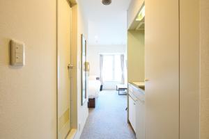 een gang met een deur die naar een kamer leidt bij Hotel Stripe Sapporo - Vacation STAY 20492 in Kita-rokujō