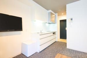a kitchen with white cabinets and a flat screen tv at Hotel Stripe Sapporo - Vacation STAY 20494 in Kita-rokujō