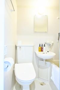 a white bathroom with a toilet and a sink at Hotel Stripe Sapporo - Vacation STAY 20493 in Kita-rokujō