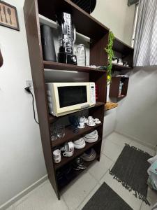 a microwave on a shelf with cups and dishes at Apartamento Estúdio em Volta Redonda - RJ in Volta Redonda +4 photos