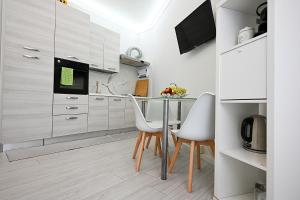 フィレンツェにあるB&B Apartaments Novoli P.Giustizのキッチン(ガラステーブル、白い椅子付)