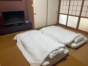 two white beds in a room with a tv at Tawaraya-Traditional Japanese-style Inn - Vacation STAY 73840v in Shimo-tahara
