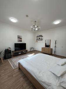 a white bedroom with a large bed and a flat screen tv at Cosy Private Suite in Suwādah