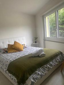 a bedroom with a bed with a green blanket and a window at Stay Inn - Meisterschwanden in Meisterschwanden