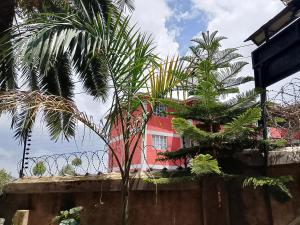 a red house behind a fence with palm trees at The Pent House Homes in Kisii +2 photos