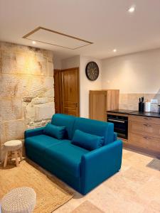 a blue couch in a living room with a clock on the wall at Gîte du Pavillon 4 pers Wi-Fi Haute Marne in Arc-en-Barrois