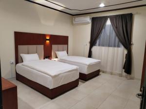 a hotel room with two beds and a window at العييري للشقق المخدومة القصيم 1 in Buraydah