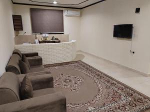 a living room with a couch and a flat screen tv at العييري للشقق المخدومة القصيم 1 in Buraydah