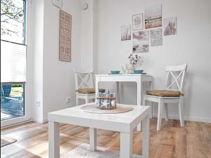 a white living room with a table and two chairs at Glück Ahoi in Insel Poel
