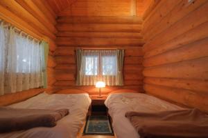 une chambre avec deux lits dans une cabane en rondins dans l'établissement Nagano - Cottage - Vacation STAY 75905v, à Chūsha