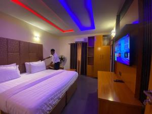 a man is standing next to a bed in a room at Beam Gate in Uyo