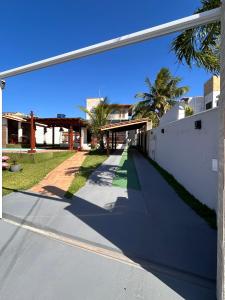 an empty street with a building and palm trees at Casa 10 com piscina em Jacuípe - Guarajuba in Camaçari