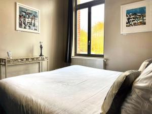 een slaapkamer met een wit bed en een raam bij T2 spacieux & calme - vue jardin, Amiens centre in La Celle-sous-Gouzon