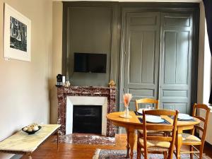 een woonkamer met een tafel en een open haard bij T2 spacieux & calme - vue jardin, Amiens centre in La Celle-sous-Gouzon