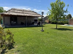 a hut with a grass roof on a yard at Wine Studio with BBQ & pool in Las Heras