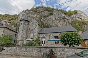 a stone building with a mountain in the background at L'Ecole in Dinant