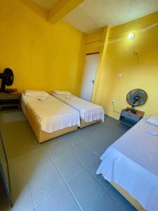 two beds in a room with yellow walls at Por do Sol Praia Hotel in Fortaleza