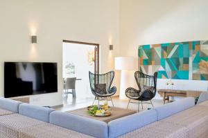 un salon avec un canapé, des chaises et une télévision dans l'établissement Villa Stoney Coral 17 - Coral Estate, à Willibrordus