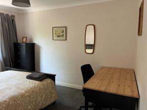 Un dormitorio con una cama, una mesa y un espejo. en Bungalow on Dartmoor's Edge, Parking & Garden, en Ashburton