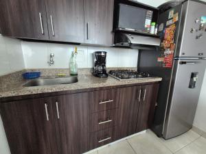 a small kitchen with a sink and a refrigerator at Cuarto amoblado en la Loma del Indio, El Poblado con vista a la ciudad in Medellín