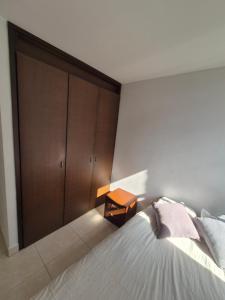 a bedroom with a bed and a wooden closet at Cuarto amoblado en la Loma del Indio, El Poblado con vista a la ciudad in Medellín