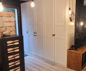 a living room with white cabinets and a tv at Apartament Szpilka - domek in Police +12 photos