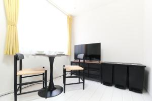 ein Wohnzimmer mit Fernseher und Tisch und Stühlen in der Unterkunft Fontaine Kamata - Vacation STAY 79354v in Tokio