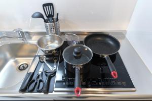 eine Küchenspüle mit Töpfen, Pfannen und Utensilien in der Unterkunft Fontaine Kamata - Vacation STAY 79354v in Tokio