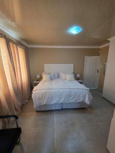 - une chambre avec un lit blanc et 2 fenêtres dans l'établissement Sweet Home Guest House, à East London