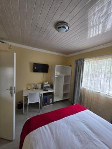 une chambre avec un lit et un bureau avec un ordinateur dans l'établissement Sweet Home Guest House, à East London