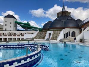 een groot zwembad voor een gebouw bij Zenora Apartman in Makó