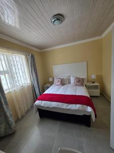 une chambre avec un grand lit recouvert d'une couverture rouge dans l'établissement Sweet Home Guest House, à East London