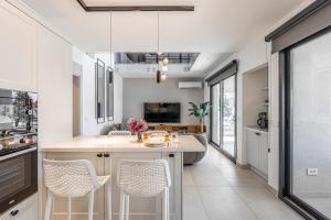une cuisine avec des placards blancs et un îlot avec des chaises dans l'établissement Villa 18 by Çimentepe Residence Deluxe, à Bodrum City