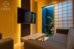 ein Wohnzimmer mit einer Couch, einem Tisch und einem Fernseher in der Unterkunft Kyoran [Phantom Flower Residence] - Vacation STAY 80036v in Kyōto + 50 Fotos