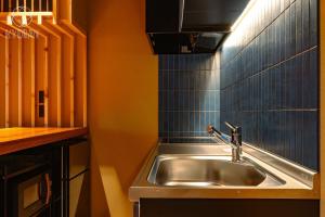 eine Küche mit einem Waschbecken und einer blau gefliesten Wand in der Unterkunft Jinglan [Orchid Residence] - Vacation STAY 80077v in Kyōto + 38 Fotos