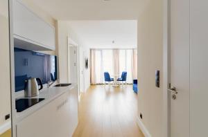 a kitchen with white counters and blue chairs at Orbi City Hotel D1 Block in Batumi
