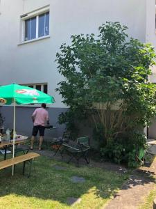 a man standing next to a table with an umbrella at Appartement dans charmante maison près de Sarrebruck in Grosbliederstroff