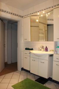 a white bathroom with a sink and a mirror at Appartement dans charmante maison près de Sarrebruck in Grosbliederstroff