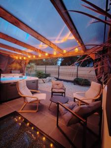 a patio with chairs and a table with lights at Évasion haut de gamme in Cléguer