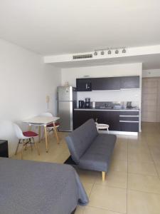 a living room with a couch and a table and a kitchen at NORDELTA BAHIA GRANDE Monoambiente con cochera in Benavídez