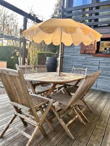 a wooden table and chairs with an umbrella on a deck at Gîte L'Écureuil - Sauna & Bain Nordique - Nature in Colroy-la-Roche