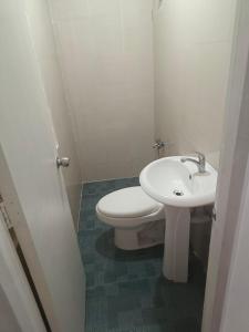 ein Badezimmer mit einer weißen Toilette und einem Waschbecken in der Unterkunft Balai Hermioni in San Pablo City