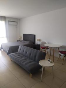 a living room with a couch and tables and a bed at NORDELTA BAHIA GRANDE Monoambiente con cochera in Benavídez +6 photos