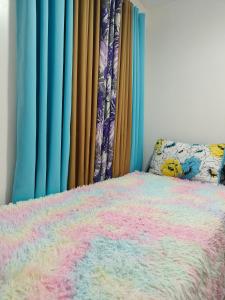 ein Schlafzimmer mit einem Bett mit einer bunten Decke in der Unterkunft Balai Hermioni in San Pablo City