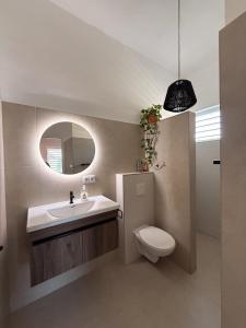 Un baño con lavabo, inodoro y espejo. en Breezy Azul Getaway, en Willemstad