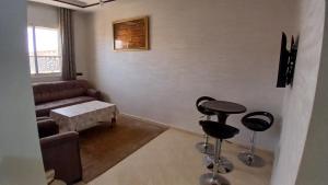 sala de estar con sofá y 2 taburetes en Appartement, en Chichaoua