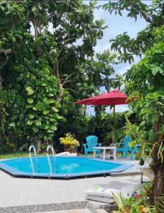 a pool with a table and chairs and an umbrella at Résidence Fleur de Café in Lamentin
