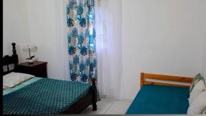 a bedroom with a bed and a blue curtain at Résidence Fleur de Café in Lamentin